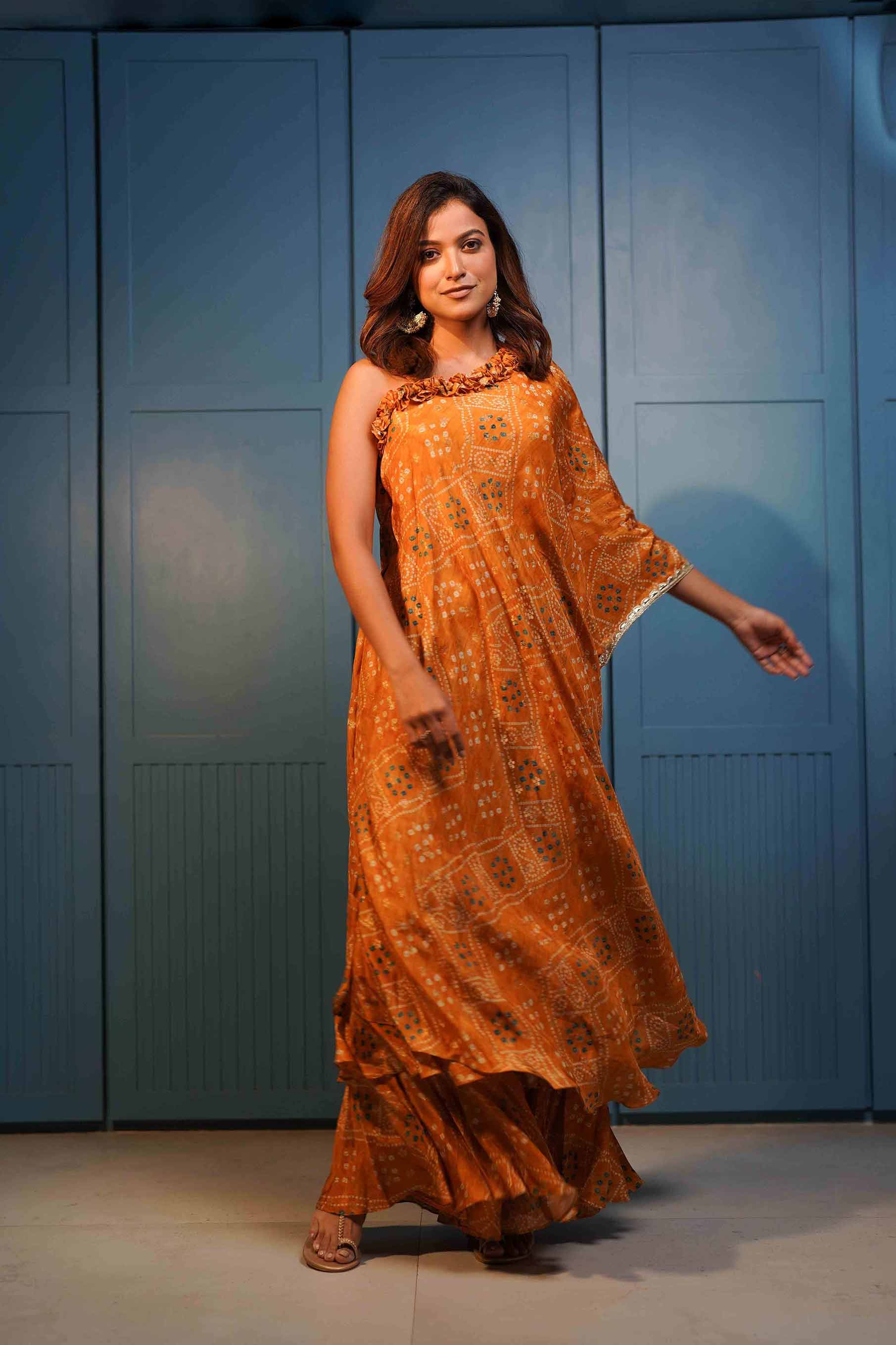 Rust yellow one shoulder tunic with ruffles paired with ruffled gharara..